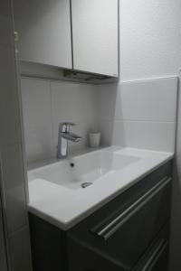 een badkamer met een witte wastafel en een kast bij Le Green Set in Pornic +14 foto's