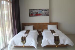 a bedroom with two beds with white comforters at Tawan Anda Garden Hotel in Suratthani