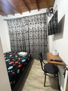 Un dormitorio con una cama y un escritorio con una computadora. en Alojamiento las palmas, en Medellín