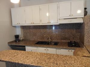 a kitchen with white cabinets and a granite counter top at Cléopâtre appartement in Hammam Sousse
