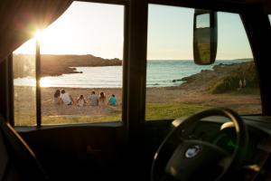 a group of people on the beach at sunset at Autocaravaning Menorca in Ferreries