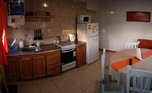 a kitchen with a stove and a refrigerator and a table at La casa de Yoni in Las Toninas