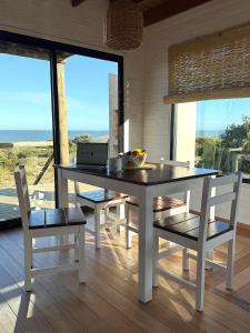 a dining room with a table and chairs and a laptop at Casa frente al mar Papaya Grande in Punta Del Diablo