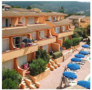 a row of apartments with blue umbrellas and tables at En Allusi Apartment in Badesi