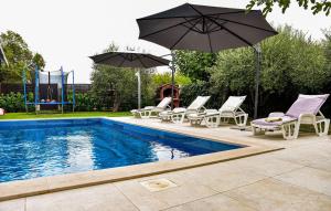 a swimming pool with chairs and umbrellas next to a pool at Nice Home In Smokovic With Wifi in Smoković