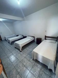 een kamer met 3 bedden en een tegelvloer bij Hotel Hebron in Três Marias