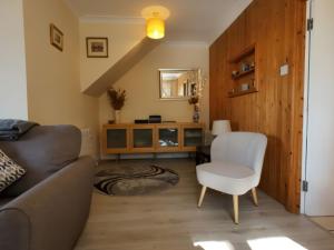 a living room with a couch and a chair at Wood End in Dalbeattie