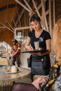 a woman holding a tray of food in a kitchen at Appartement Walvis nr 26 in Vrouwenpolder