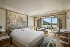 Un dormitorio con una gran cama blanca y una sala de estar. en Udaipur Marriott Hotel, en Udaipur
