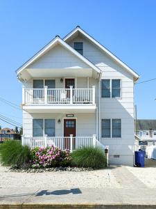 ein weißes Haus mit einem Balkon und Blumen in der Unterkunft Wifi, Outdoor Shower, Deck, Ocean Side 2Nd Floor Duplex Ocean Side 1St Floor Duplex, A Short Walk From The Best Lbi Attractions, A Small Park, And, in Beach Haven