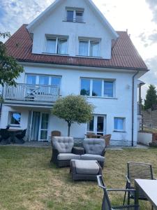 a white house with couches and chairs in the yard at Willa Róż Wisełka in Wisełka