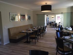 a dining room with tables and chairs and a couch at Hotel und Restaurant Kranichsberg in Woltersdorf