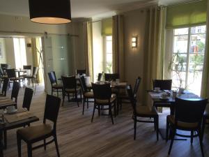 a dining room with tables and chairs and windows at Hotel und Restaurant Kranichsberg in Woltersdorf