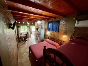 a room with two beds and a living room with a kitchen at Departamentos La Morita in Embalse