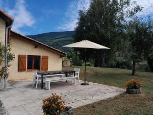 un banc et un parasol devant une maison dans l'établissement Maison de montagne, à Soulan