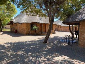 Un edificio de ladrillo con un árbol delante. en Jarina Guesthouse, en Wolmaranstad