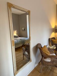 a mirror in a room with two chairs and a bed at Rindö Hamn Bed & Breakfast in Vaxholm