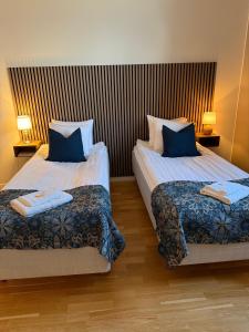 two beds in a hotel room with blue pillows at Rindö Hamn Bed & Breakfast in Vaxholm