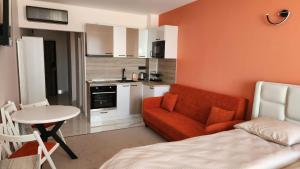 a living room with a red couch and a kitchen at Димоти Апартхотел in Sofia