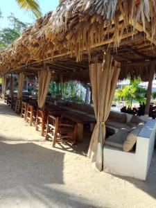 a straw hut with tables and chairs under it at Villa Don Julio in Juan Dolio +7 photos