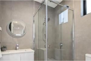 a shower with a glass door in a bathroom at Domi Rentals - The Moorabbin Townhouse in Moorabbin