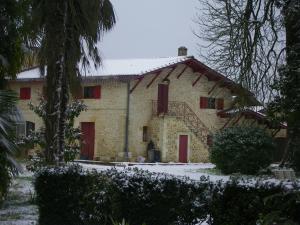 バルサックにあるChâteau Dudonの雪中の赤い扉のある石造りの家