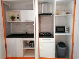 una cucina con mobili bianchi, un lavello e un microonde di Gîte les iris Laroque 34 DOUBLON a Laroque