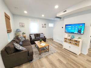 a living room with a couch and a flat screen tv at The Sand Star-4BDRM Ventnor Home near Bay & AC in Ventnor City