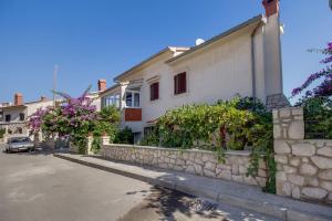 a house with a stone wall next to a street at Apartments Suzana in Mali Lošinj
