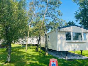 a white tiny house in a yard with trees at Wensleydale 17 Caravan in Tosside +7 photos