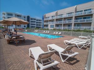 une piscine avec des chaises longues et un parasol dans l'établissement TideWatch-Relax in Brigantine w/Views,Beach & Pool, à Brigantine