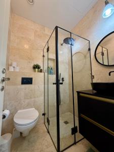 a bathroom with a toilet and a glass shower at Lovely 1-bedroom apartment in The best location in Tel Aviv