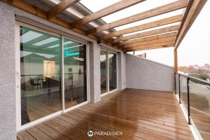an outdoor deck with glass doors and a wooden ceiling at Paradisier in Villars-les-Dombes