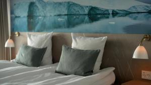 a bedroom with a bed with pillows and a painting at Hotel Arctic in Ilulissat