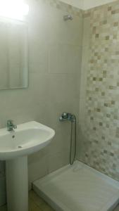 a white bathroom with a sink and a shower at Nefeli in Lefkos Karpathou