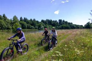 three people riding bikes in a field near a river at Les Palafitos in Luglon