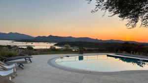 a swimming pool with a sunset in the background at Villa Carlotta in San Teodoro