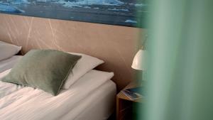 a bedroom with a bed with a green pillow on it at Hotel Arctic in Ilulissat