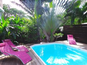 - une piscine avec deux chaises violettes à côté dans l'établissement Villa CHANTEVENT - vue mer et piscine - plage à pied, à Deshaies