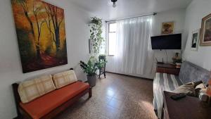 a living room with a couch and a tv at Quarto da Orla in Cabo Frio