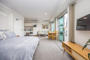 a bedroom with a bed and a living room and a kitchen at Princes Wharf with HUGE deck!! in Auckland