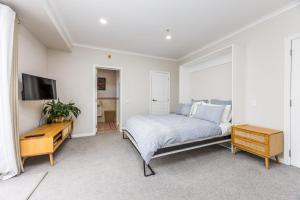 a bedroom with a bed and a desk and a tv at Princes Wharf with HUGE deck!! in Auckland