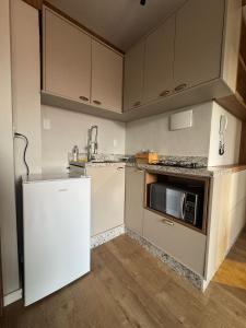 バウネアーリオ・コンボリウーにあるApartmento em Balneário Camboriúの冷蔵庫と電子レンジ付きのキッチン +3枚の写真