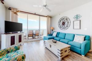 a living room with a blue couch and a tv at The Beach Club 1101C in Gulf Highlands