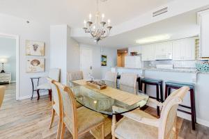 a dining room and kitchen with a glass table and chairs at The Beach Club 1101C in Gulf Highlands