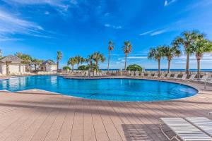 a large swimming pool with palm trees and the ocean at The Beach Club 1102B in Gulf Highlands