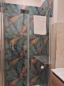 a shower in a bathroom with a mural of leaves at La Petite Maison in Naples