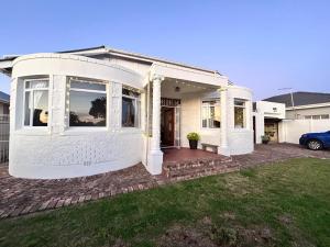a white house with a car parked in front of it at Bottlebrush Guest Suite - close to Greenacres Hospital, Free WiFi, Parking, private in Gqeberha