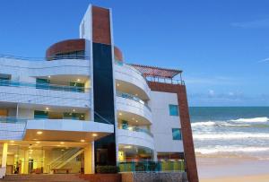a building on the beach next to the ocean at Calhau Praia Hotel in São Luís