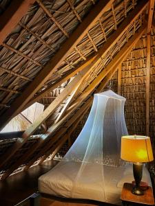 a bed in a attic with a lamp on a table at Cabañas Uma 2 in San Agustinillo